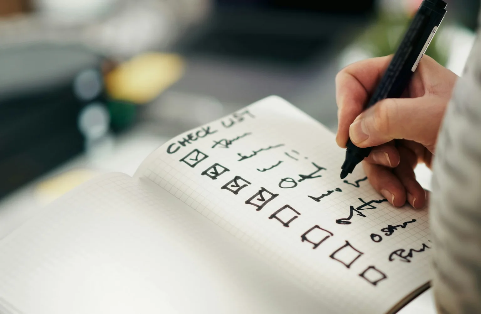 A hand marking completed items on a paper checklist